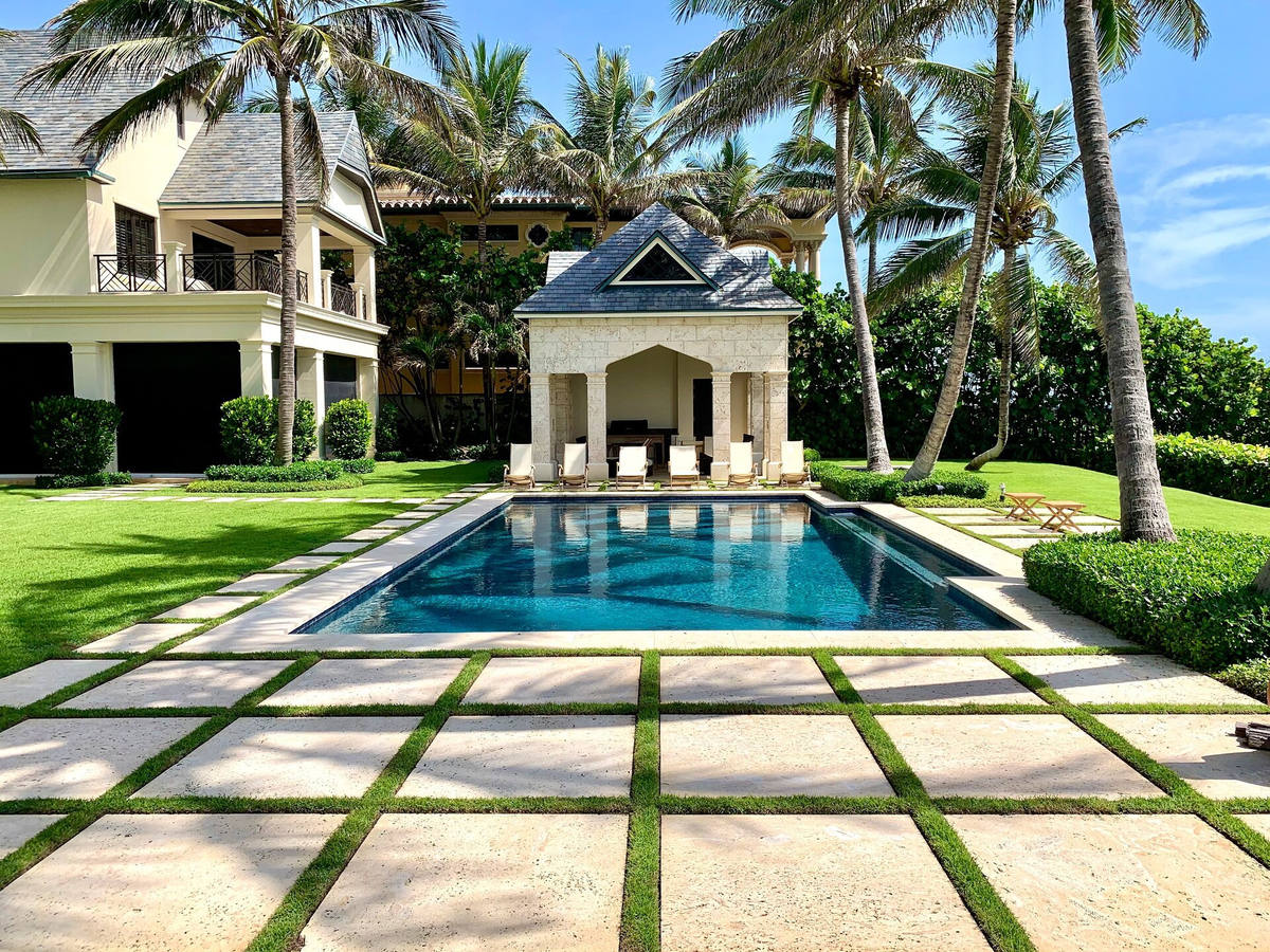 Pool terrace with stone pavers, turf joints and clipped hedges at a South Florida estate