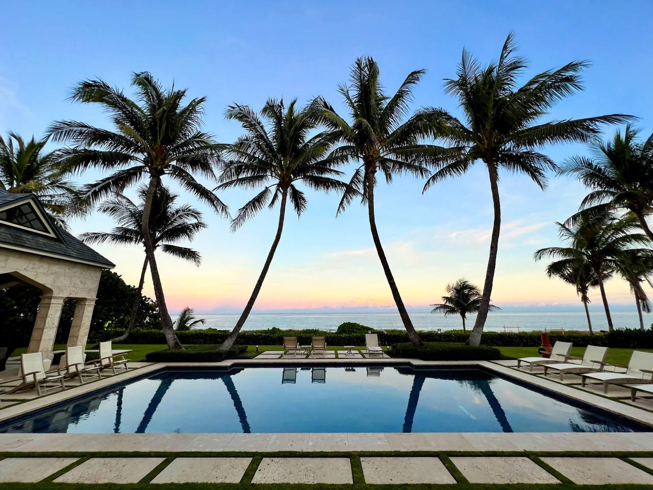 Oceanfront pool terrace and palms at dusk at a South Florida estate